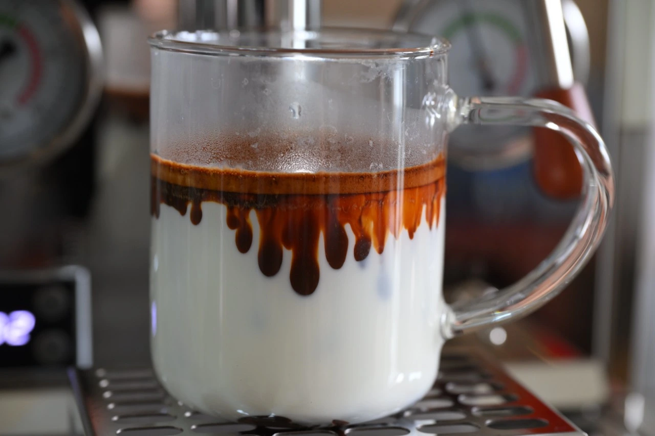 Espresso entering milk, with brown coffee slowly spreading into white milk.